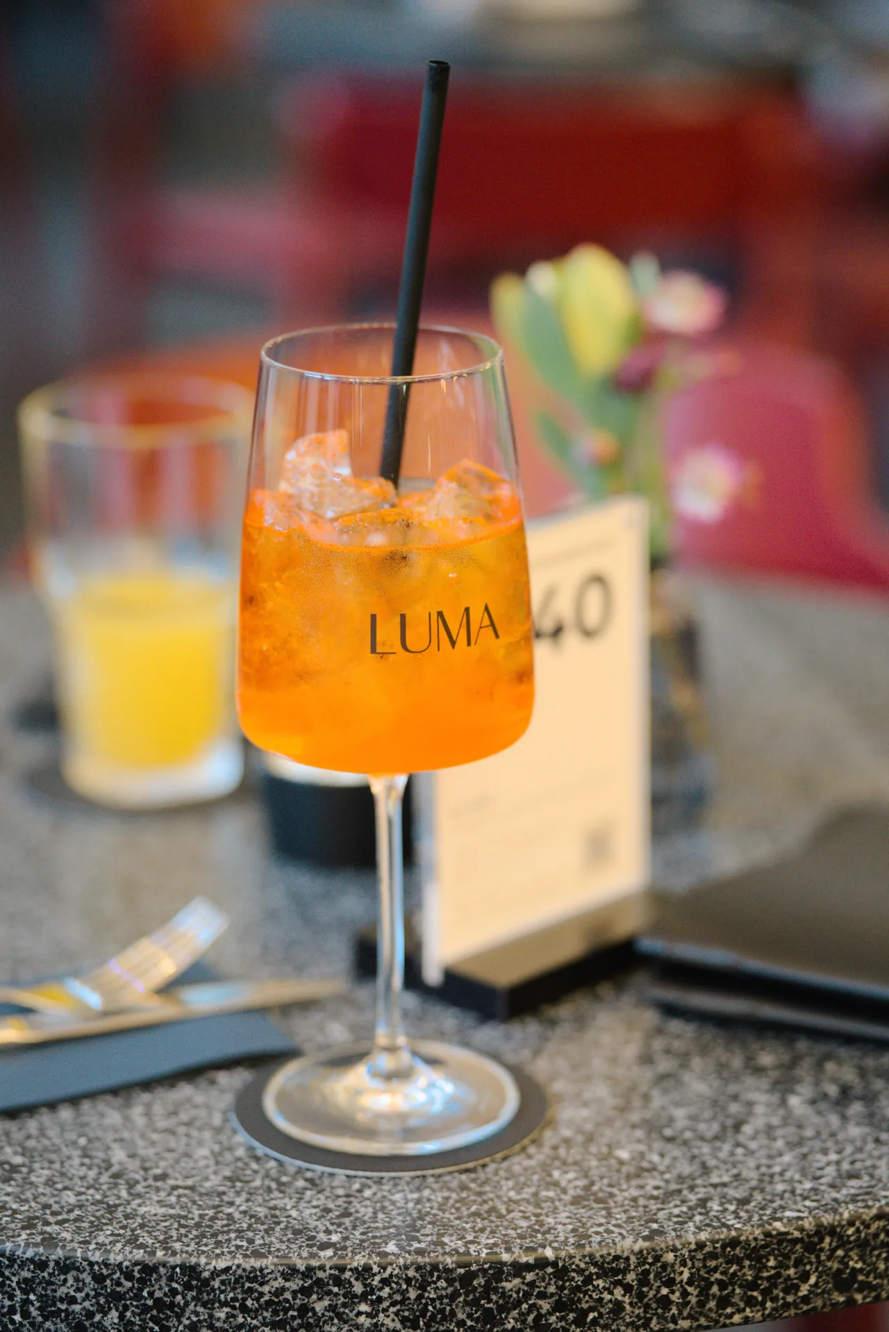 Orangefarbener Drink im LUMA-Stielglas auf einem Steintisch